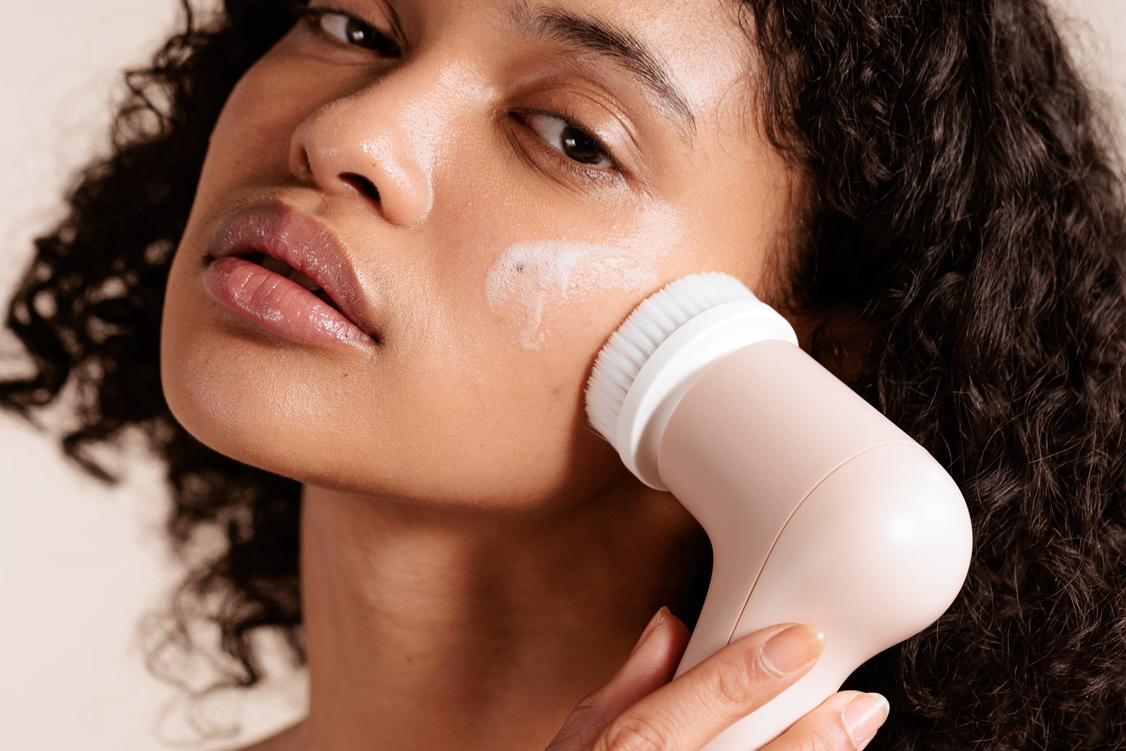 A person using an electric facial cleansing brush during a skincare routine